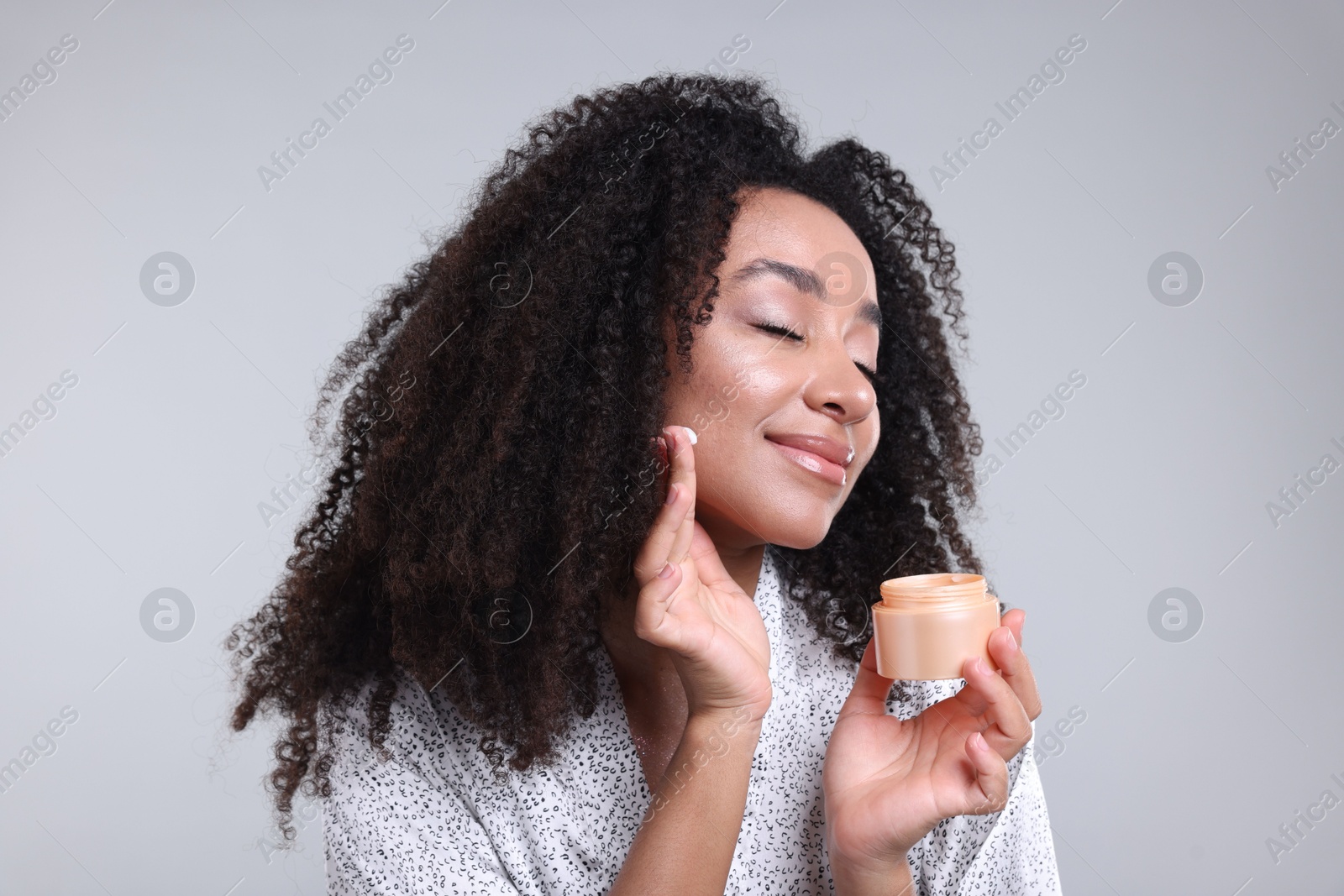 Beautiful Brazilian woman with jar of collagen cream on gray background Photo of Beautiful Brazilian woman with jar of collagen cream on gray background
