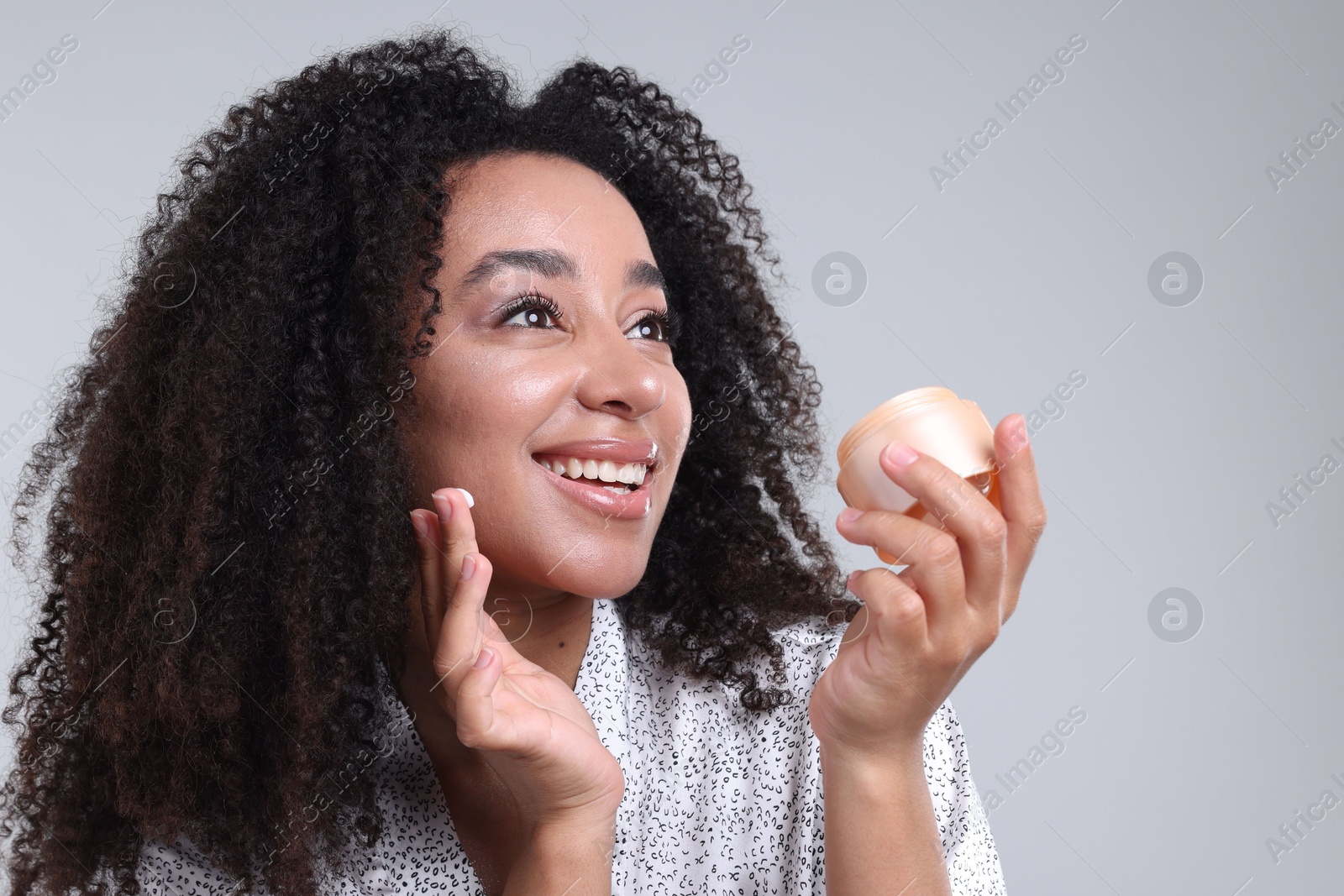 Beautiful Brazilian woman with jar of collagen cream on gray background Photo of Beautiful Brazilian woman with jar of collagen cream on gray background