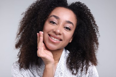 Photo of Beautiful Brazilian woman with collagen cream on gray background