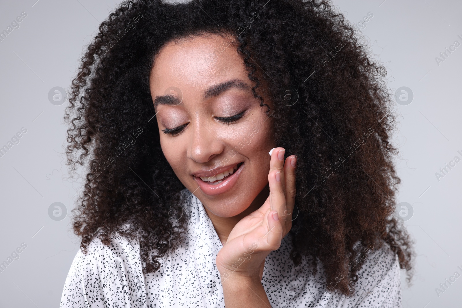 Beautiful Brazilian woman with collagen cream on gray background Photo of Beautiful Brazilian woman with collagen cream on gray background