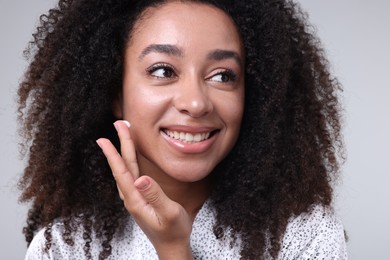 Photo of Beautiful Brazilian woman with collagen cream on gray background, closeup