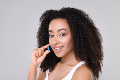 Photo of Beautiful Brazilian woman with collagen pill on gray background