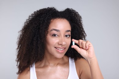 Photo of Beautiful Brazilian woman with collagen pill on gray background