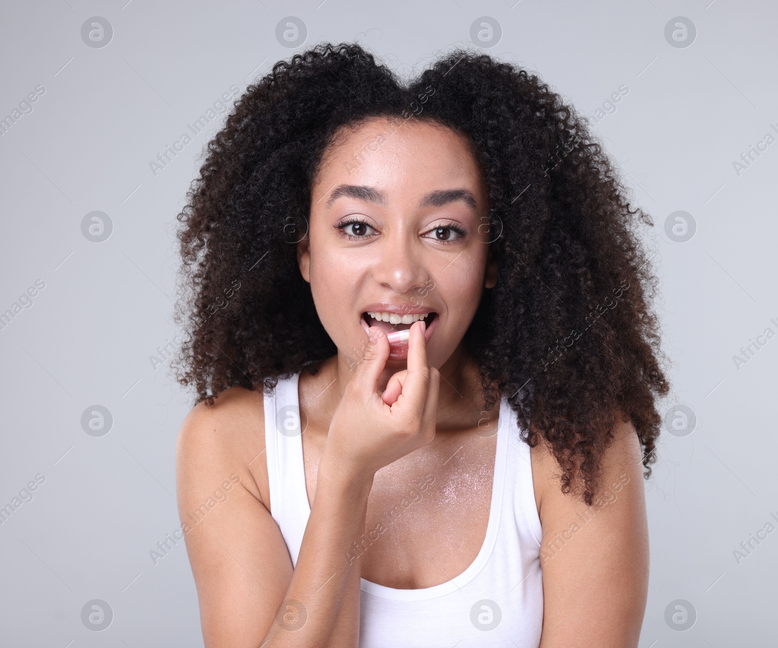 Beautiful Brazilian woman taking collagen pill on gray background Photo of Beautiful Brazilian woman taking collagen pill on gray background
