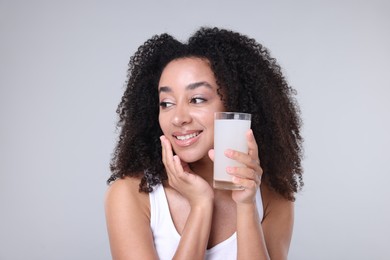 Photo of Beautiful Brazilian woman with glass of collagen water on gray background