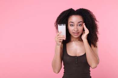 Photo of Beautiful Brazilian woman with glass of collagen water on pink background. Space for text