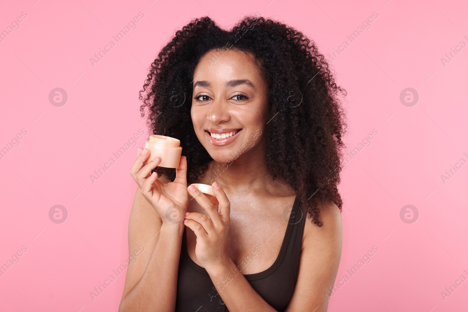 Beautiful Brazilian woman with jar of collagen cream on pink background Photo of Beautiful Brazilian woman with jar of collagen cream on pink background