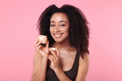 Photo of Beautiful Brazilian woman with jar of collagen cream on pink background
