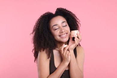 Photo of Beautiful Brazilian woman with jar of collagen cream on pink background