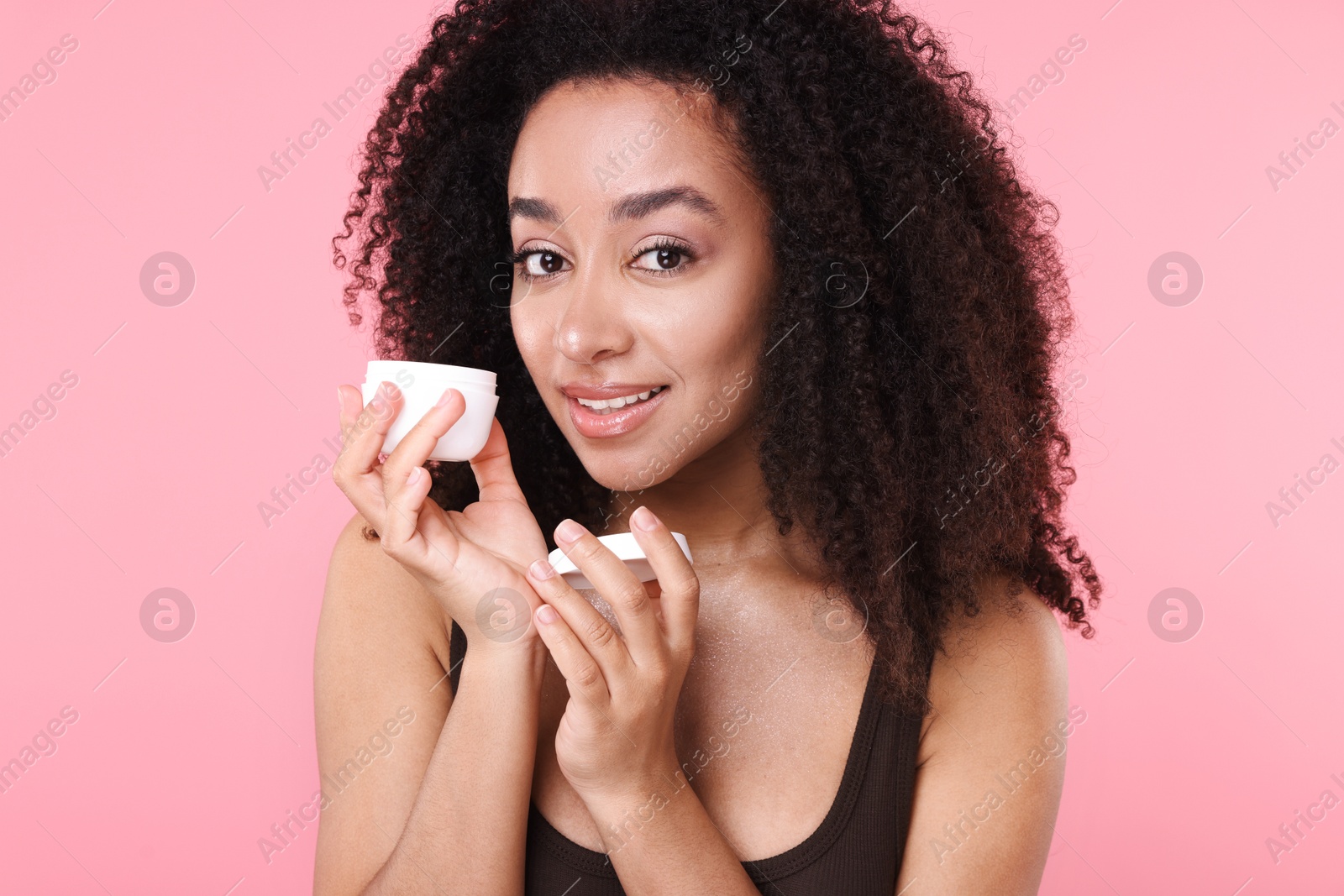 Beautiful Brazilian woman with jar of collagen cream on pink background Photo of Beautiful Brazilian woman with jar of collagen cream on pink background