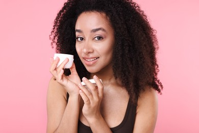 Photo of Beautiful Brazilian woman with jar of collagen cream on pink background