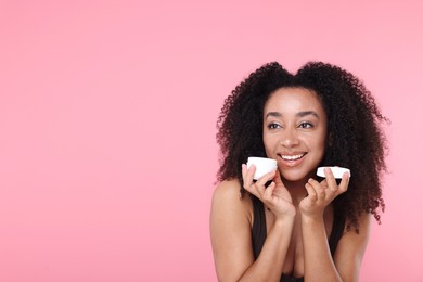 Photo of Beautiful Brazilian woman with jar of collagen cream on pink background. Space for text
