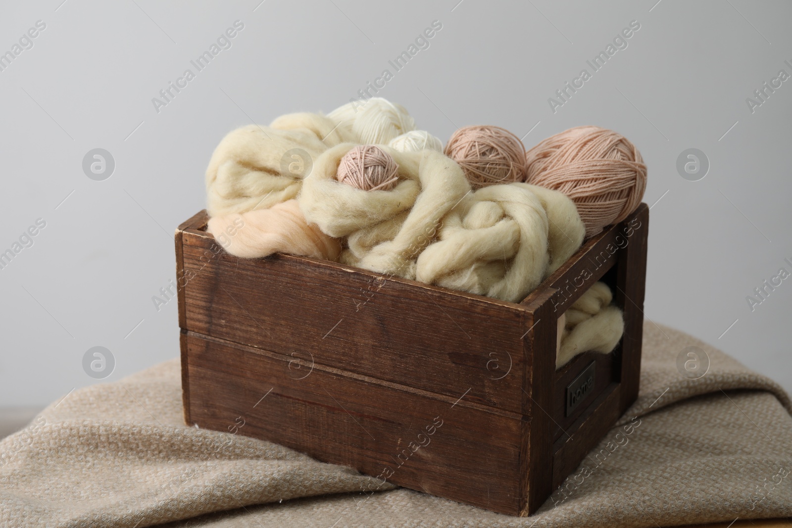 Soft felting wool and knitting yarn in wooden basket on grey background Photo of Soft felting wool and knitting yarn in wooden basket on grey background