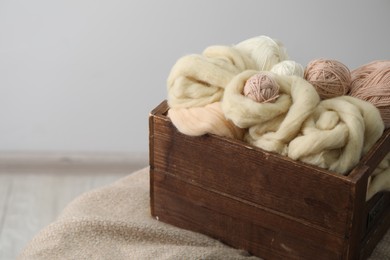 Photo of Soft felting wool and knitting yarn in wooden basket on grey background, closeup. Space for text
