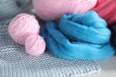 Photo of Soft felting wool and knitting yarn on white wooden table, closeup