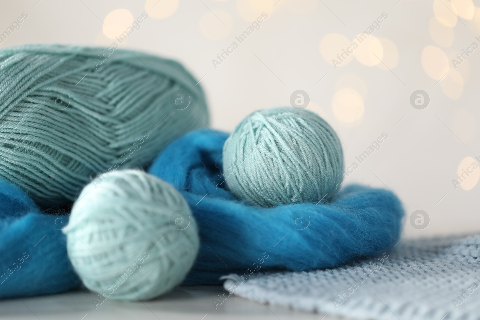 Soft felting wool and knitting yarn on white wooden table against blurred lights, closeup Photo of Soft felting wool and knitting yarn on white wooden table against blurred lights, closeup