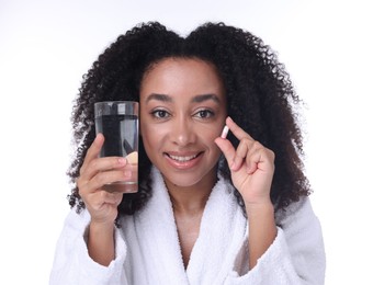 Photo of Beautiful Brazilian woman with glass of water and collagen pill on white background