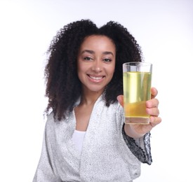 Photo of Beautiful Brazilian woman with glass of collagen water on white background, selective focus