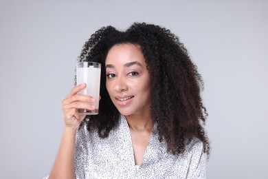 Photo of Beautiful Brazilian woman with glass of collagen water on gray background