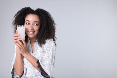Photo of Beautiful Brazilian woman with glass of collagen water on gray background. Space for text