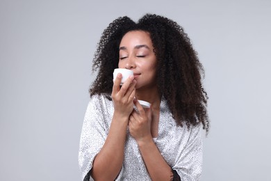 Photo of Beautiful Brazilian woman with jar of collagen cream on gray background