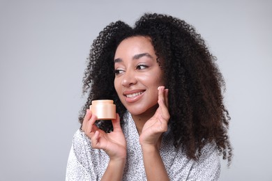 Photo of Beautiful Brazilian woman with jar of collagen cream on gray background