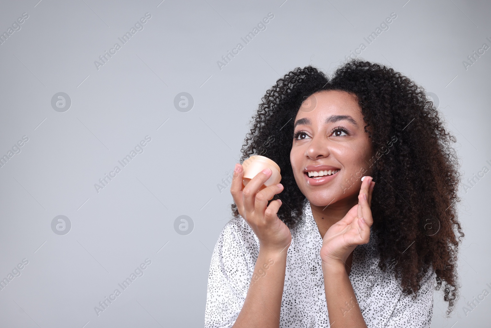 Beautiful Brazilian woman with jar of collagen cream on gray background. Space for text Photo of Beautiful Brazilian woman with jar of collagen cream on gray background. Space for text