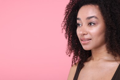 Photo of Beautiful Brazilian woman with healthy skin on pink background, closeup. Space for text