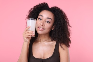 Photo of Beautiful Brazilian woman with glass of collagen water on pink background
