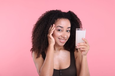 Photo of Beautiful Brazilian woman with glass of collagen water on pink background