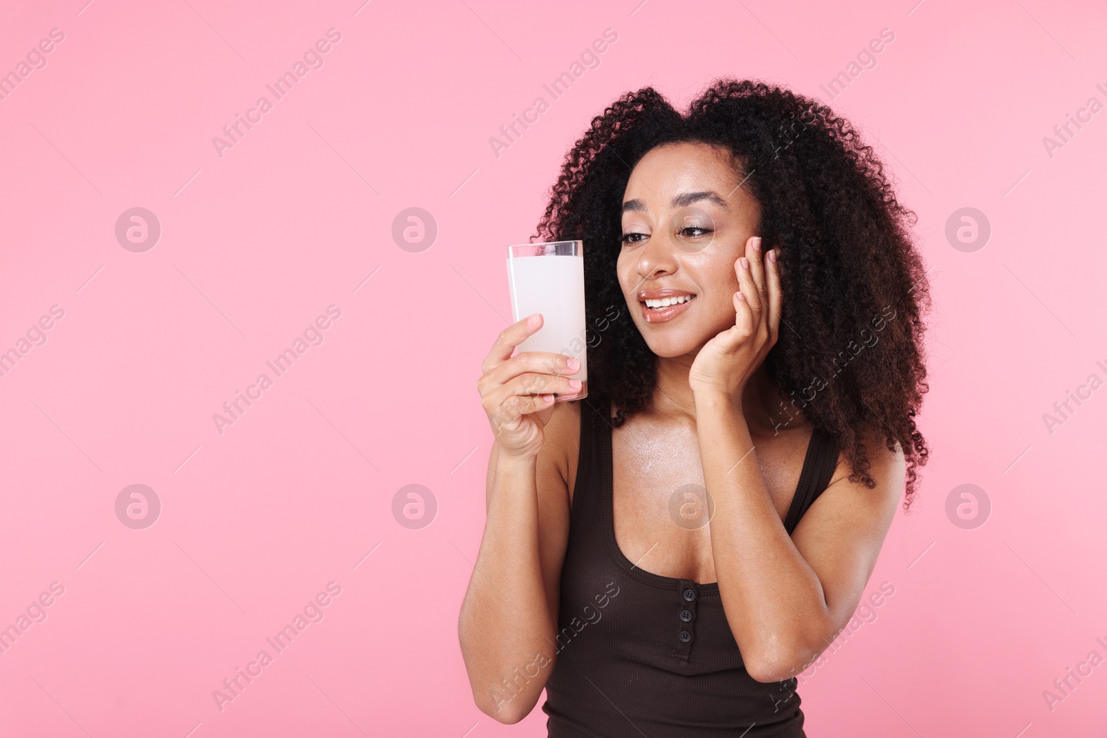 Beautiful Brazilian woman with glass of collagen water on pink background. Space for text Photo of Beautiful Brazilian woman with glass of collagen water on pink background. Space for text