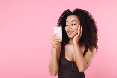 Photo of Beautiful Brazilian woman with glass of collagen water on pink background. Space for text
