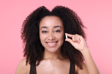 Photo of Beautiful Brazilian woman with collagen pill on pink background