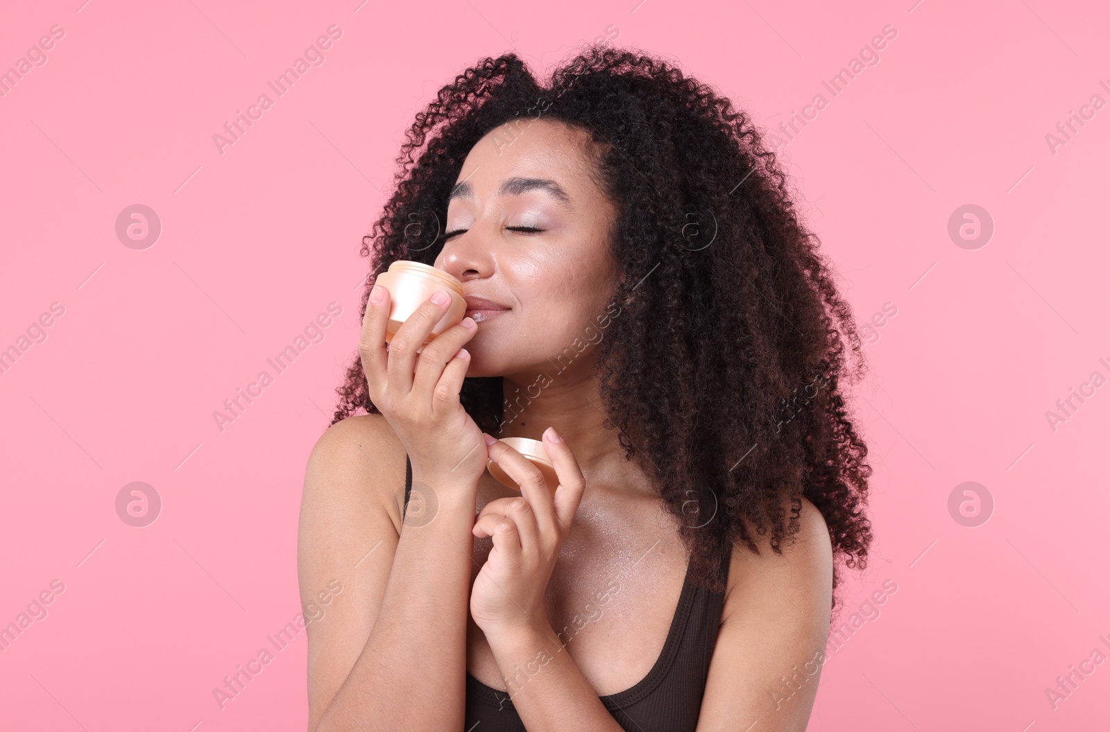Beautiful Brazilian woman with jar of collagen cream on pink background Photo of Beautiful Brazilian woman with jar of collagen cream on pink background