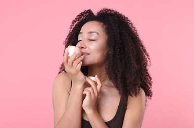 Photo of Beautiful Brazilian woman with jar of collagen cream on pink background