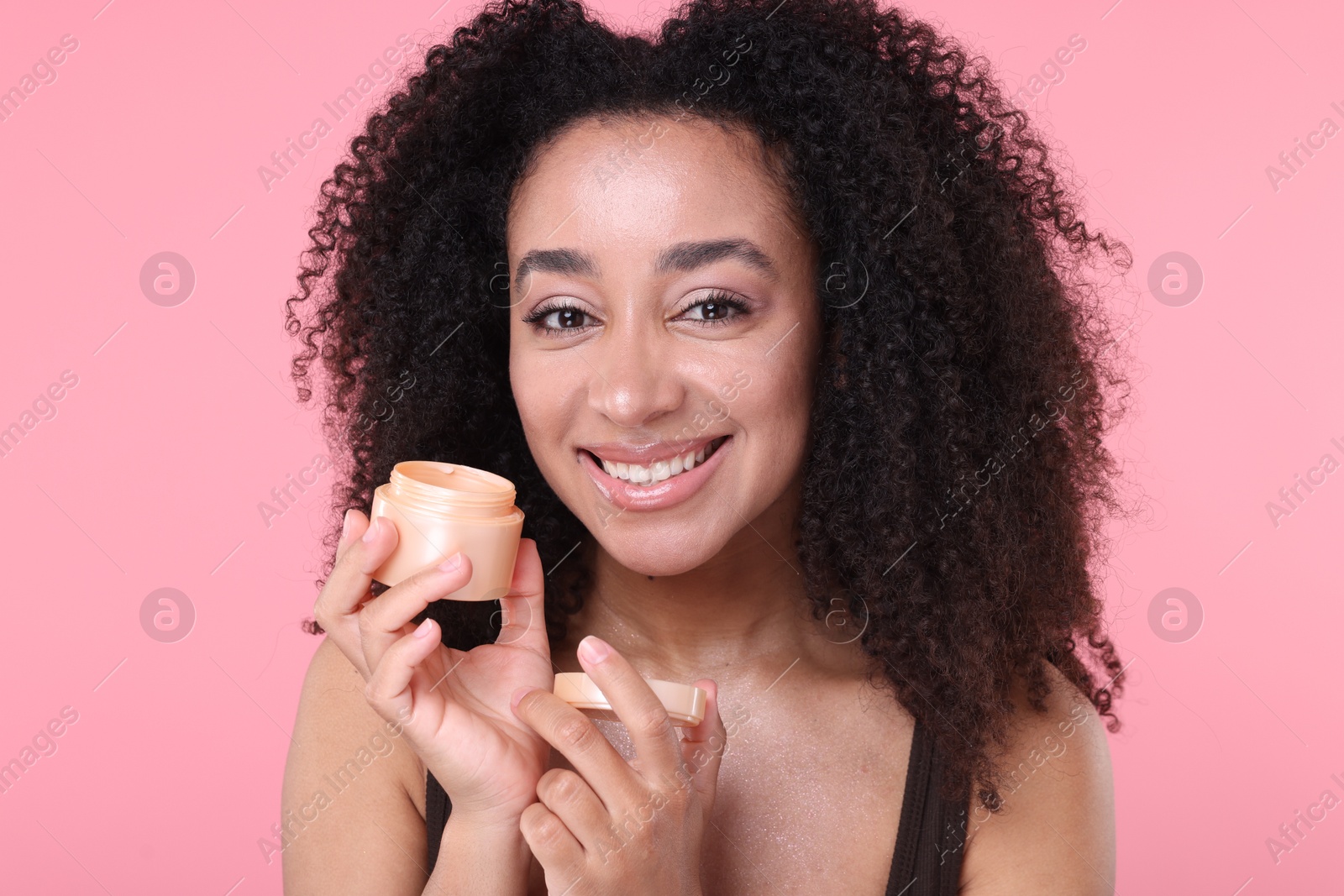 Beautiful Brazilian woman with jar of collagen cream on pink background Photo of Beautiful Brazilian woman with jar of collagen cream on pink background
