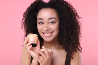 Photo of Beautiful Brazilian woman with jar of collagen cream on pink background