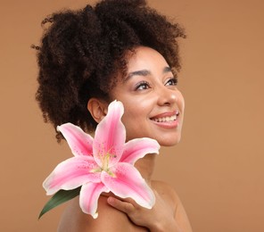 Photo of Portrait of beautiful Brazilian woman with lily flower after spa treatment on light brown background