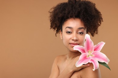 Photo of Portrait of beautiful Brazilian woman with lily flower after spa treatment on light brown background. Space for text
