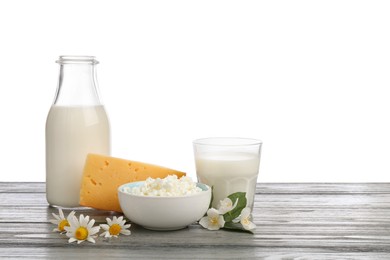 Photo of Different fresh dairy products and flowers on grey wooden table against white background