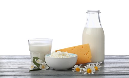 Photo of Different fresh dairy products and flowers on grey wooden table against white background