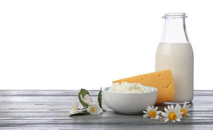 Photo of Different fresh dairy products and flowers on grey wooden table against white background