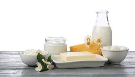 Photo of Different fresh dairy products and flowers on grey wooden table against white background
