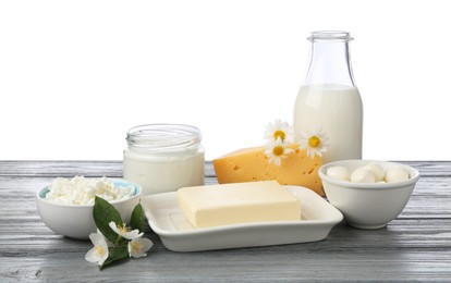 Photo of Different fresh dairy products and flowers on grey wooden table against white background