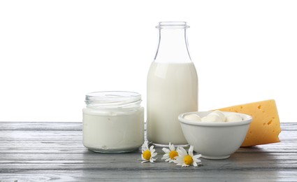 Photo of Different fresh dairy products and chamomile flowers on grey wooden table against white background