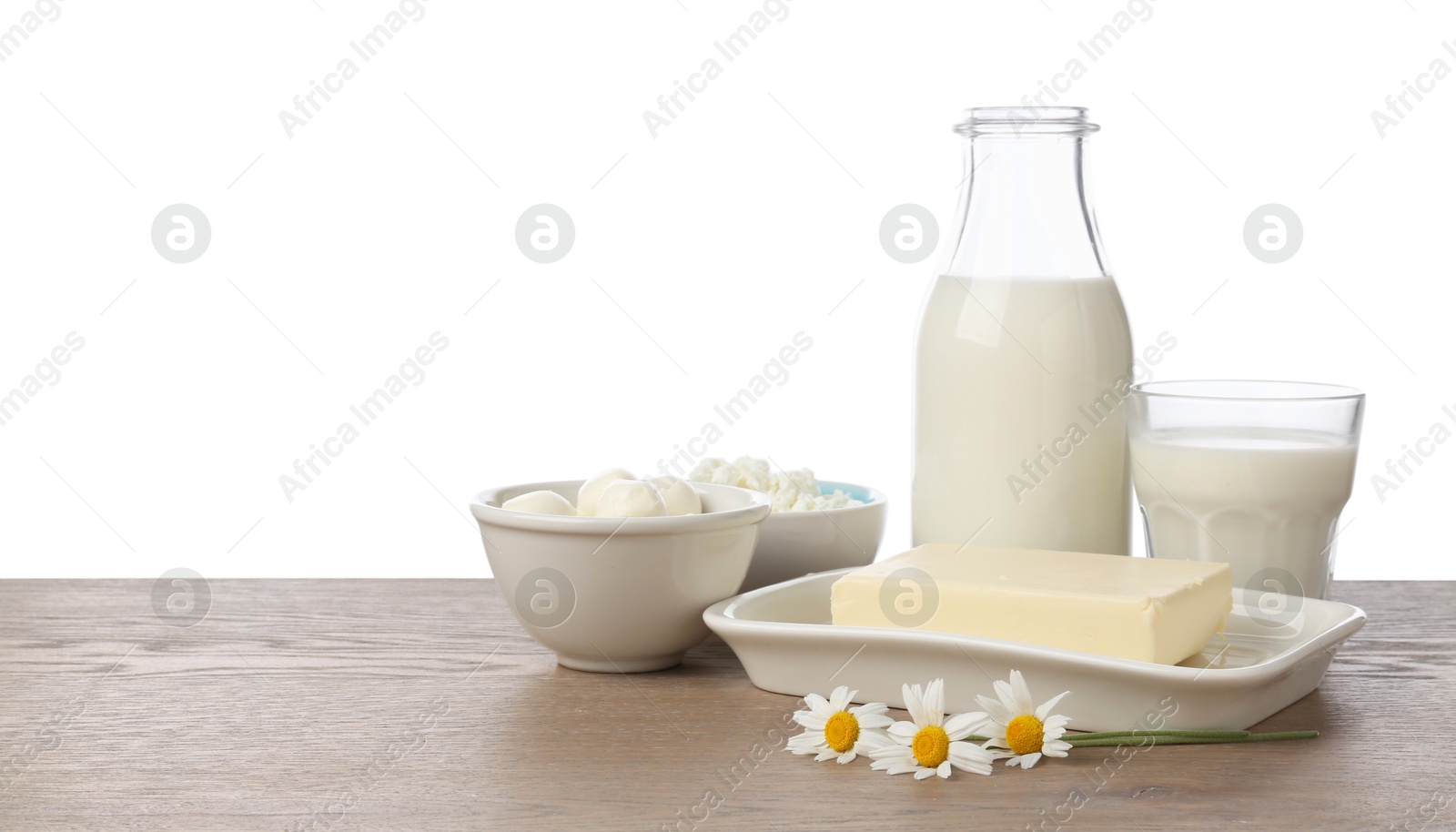 Photo of Different fresh dairy products and chamomile flowers on wooden table against white background