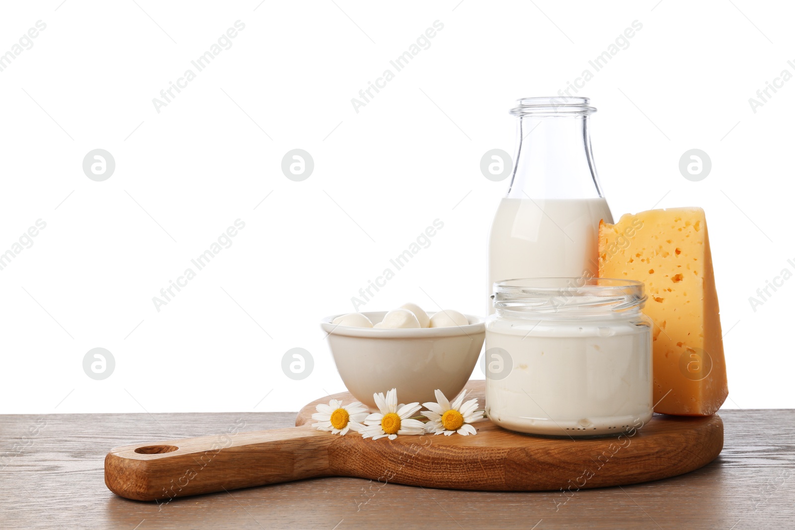 Photo of Different fresh dairy products and chamomile flowers on wooden table against white background