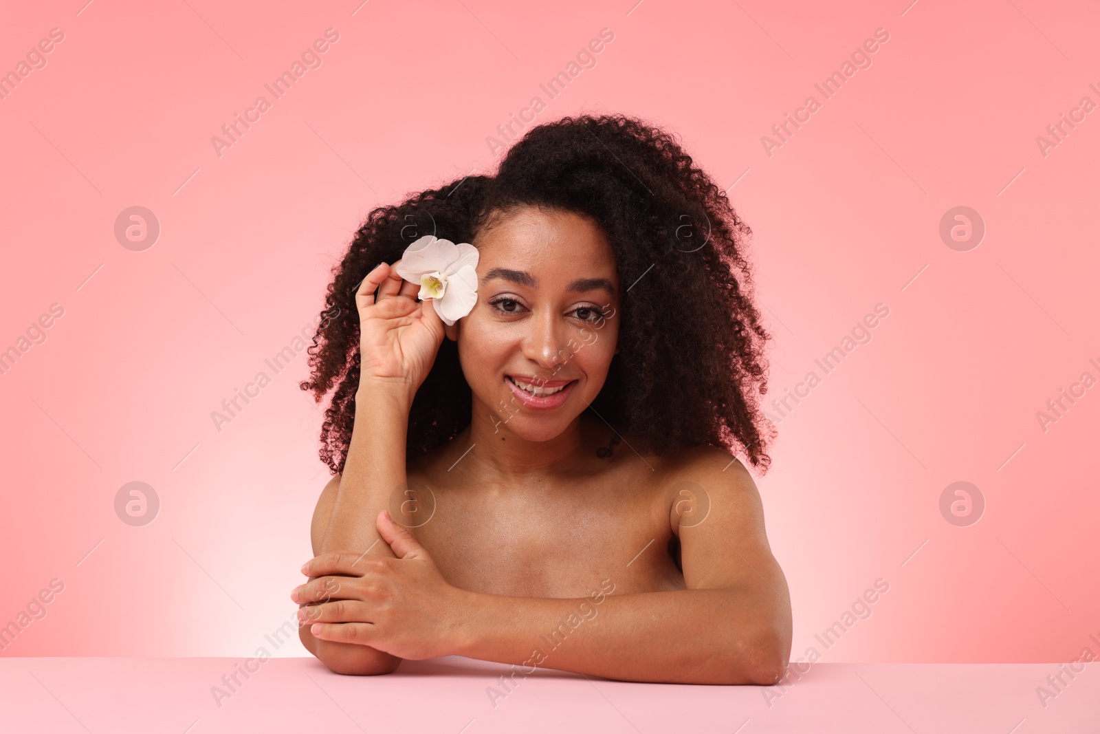 Portrait of beautiful Brazilian woman with orchid flower after spa treatment on pink gradient background Photo of Portrait of beautiful Brazilian woman with orchid flower after spa treatment on pink gradient background