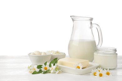Photo of Different fresh dairy products and flowers on wooden table against white background