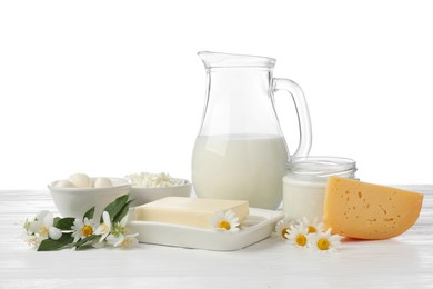 Photo of Different fresh dairy products and flowers on wooden table against white background